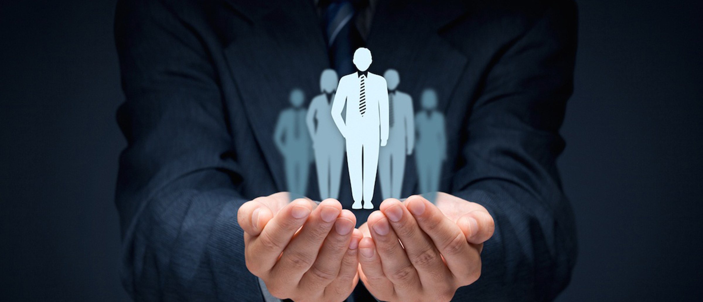 Businessperson holding their hands open with a white human figurine in front of other faded figurines