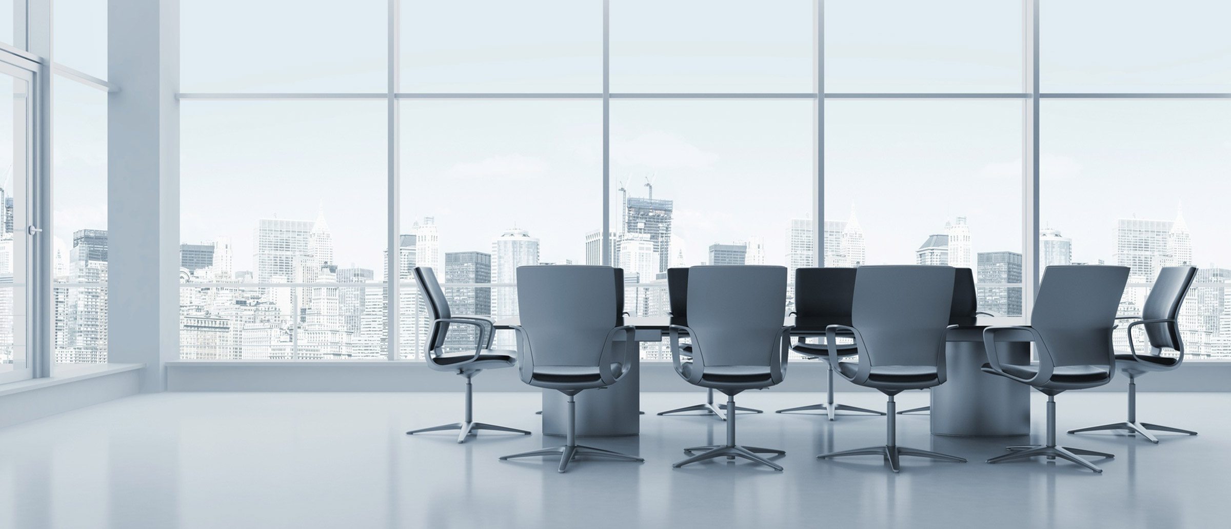 Empty room with a conference table and glass windows overlooking a city skyline